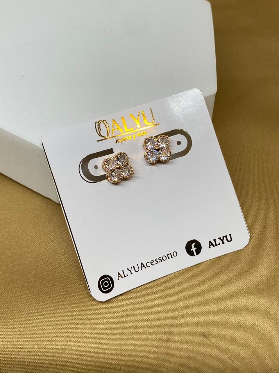 A26420 Arete trébol con piedra blanca Material: Oro Laminado 18K.