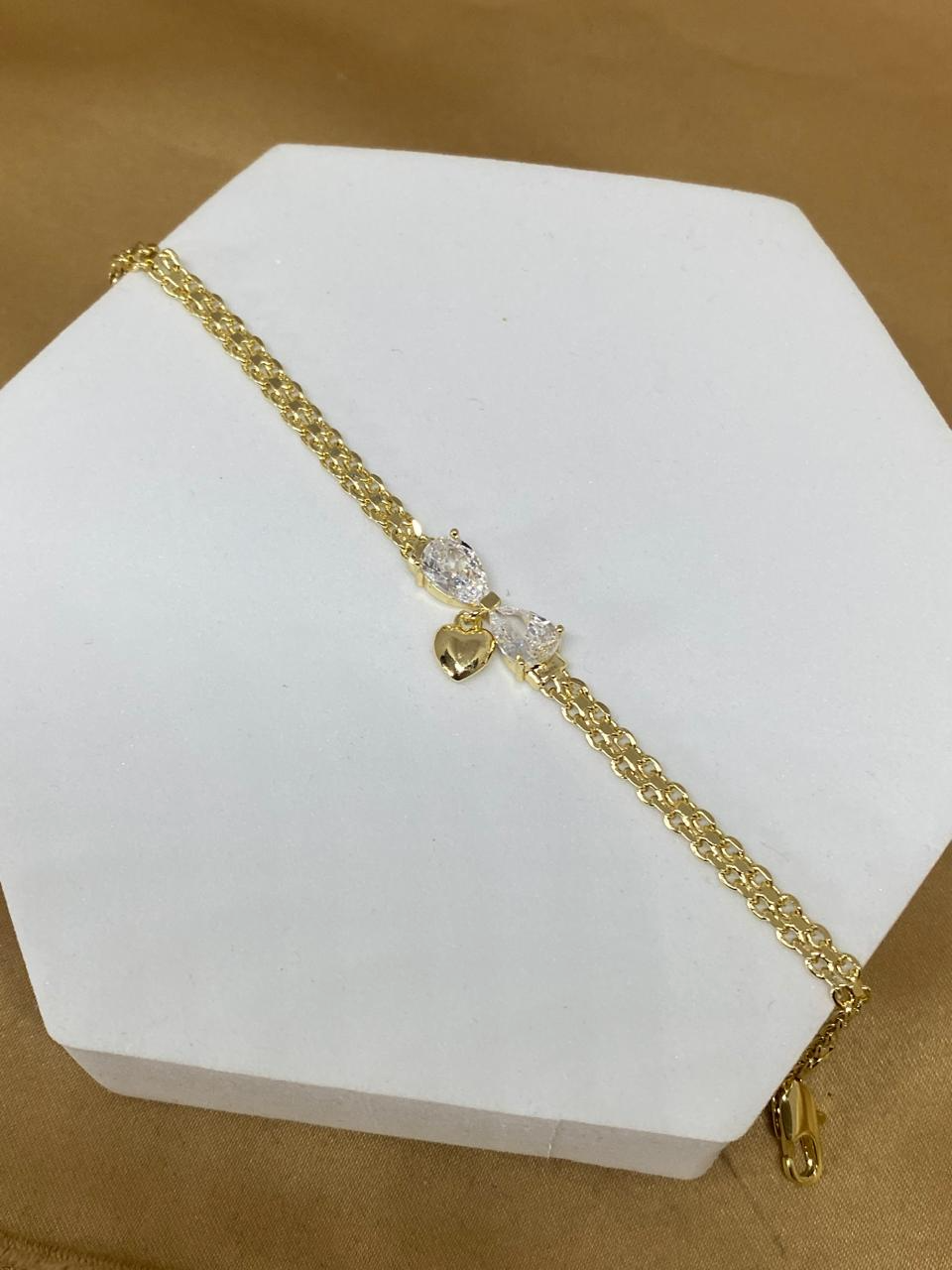P26493 pulsera moño con corazón colgante Material: Oro Laminado 14k.